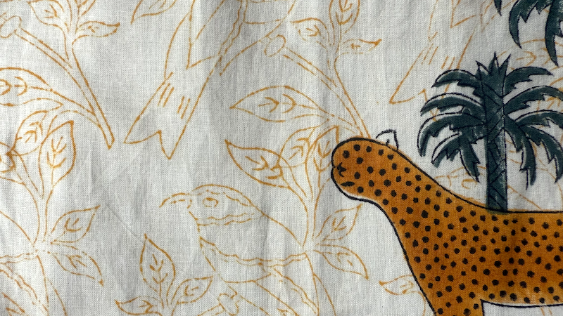 Textile with leopard and palm tree design on a neutral background